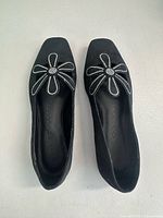 Top view of both flats showing rhinestone daisy embellishments and square toe design