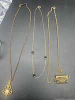 All three gold-tone necklaces laid flat showing pendants and chain styles
