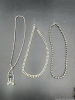 Three necklaces laid out side by side showing full lengths and styles