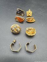 All four pairs of earrings arranged on dark surface