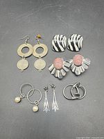 All six pairs of earrings arranged on dark background