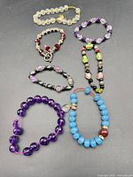 Seven assorted bracelets displayed on dark background