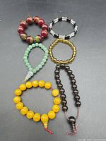 Six assorted beaded bracelets laid out on black background