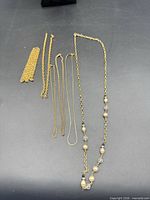 All seven gold-tone necklaces laid out