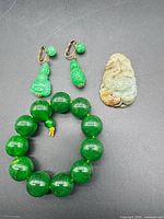 Bracelet, earrings pair and carved pendant laid out