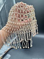 Hair cap held in hand showing lattice pattern and dangling strands