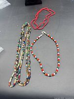 Overview of three bead necklaces on black surface