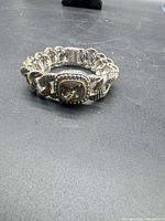 Bracelet coiled on flat surface showing links and centerpiece