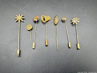 All eight gold-tone stick pins laid out in a row
