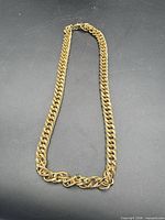 Full view of gold-tone curb link necklace laid flat