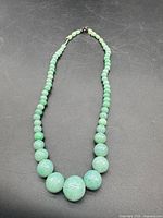 Full view of graduated jade bead necklace laid flat showing overall design