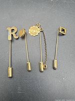 Full set of four gold-tone stick pins displayed