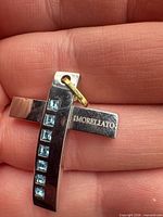 Front of cross pendant showing blue stones and engraved MORELLATO