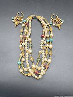 Full view of three-strand necklace and pair of hoop earrings