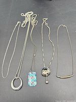Four silver-tone necklaces laid out side by side
