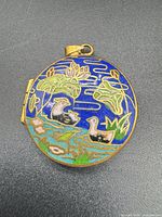 front of round cloisonné locket showing duck and lotus design