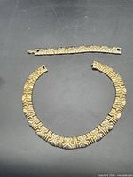 Collar necklace and bracelet laid flat showing full design