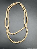 Full view of double-strand cream pearl necklace laid flat