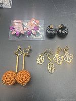 All five pairs of earrings laid out on black surface