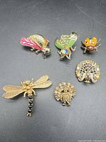 Six animal brooches arranged on black background