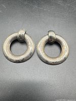 Front view of both circular silver-tone door knocker earrings