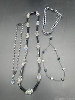 All four necklaces laid out on black background