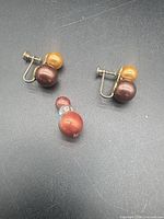 Two screw-back earrings and pendant laid out on dark surface