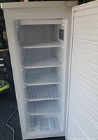 Freezer door open showing five wire shelves and interior condition