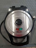 Top view showing stainless lid, indicator lights, dial and cord