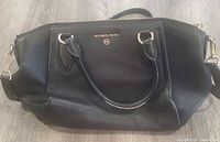 Front view of black Michael Kors pebbled leather satchel with handles and detachable strap