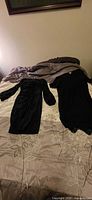 Overview of both black dresses laid out on bed