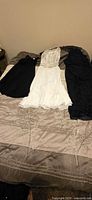 All three dresses laid out on bed: white center, black left and right