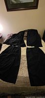 Four dark skirts laid out on bed for full lot view