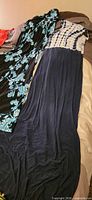 Two dresses laid out: black with aqua floral print, and navy with tie-dye bodice