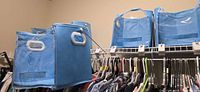 Four blue collapsible storage bins on closet shelf