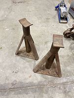 Two vintage triangular jack stands with blue floor jack visible