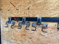 Rail mounted on wall with multiple utility hooks attached