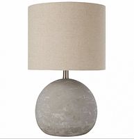 Full view of gray concrete base lamp with beige drum shade