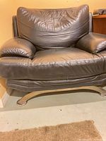 Front view of black faux leather armchair on metal base