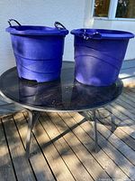 Two blue plastic tubs on glass table showing overall form and color