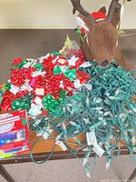 Lot overview showing gift bows pile, green wired string lights, plush reindeer