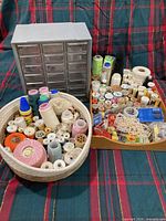 Overall lot showing plastic drawer organizer, woven basket filled with thread spools and wooden tray with additional notions