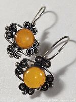 Front view of both earrings showing amber cabochons and scrollwork