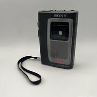 Front view showing Sony branding, cassette window, speaker grille and wrist strap