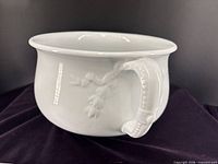 Side view of white ironstone chamber pot showing handle and embossed vine detail