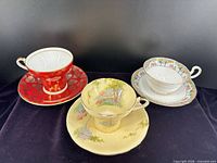 Front view of the three patterned Aynsley teacup and saucer sets