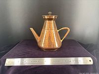 Full view of copper teapot with ruler for scale