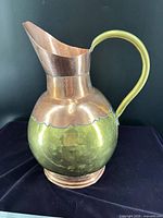 Front left view of two-tone brass and copper pitcher with handle and spout