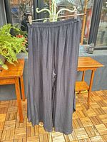 Front view of black wide leg palazzo pants hanging to show full length and drape