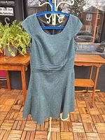Front view of teal fit-and-flare dress on hanger showing overall style and condition